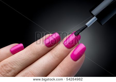 Beautiful manicure process. Nail polish being applied to hand. Black backgrou