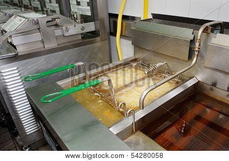 Deep fryer with boiling oil in junk food restaurant