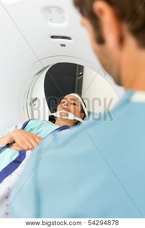 Female patient looking at nurse while undergoing CT scan test in examination room