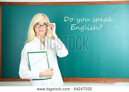 School teacher near blackboard in classroom