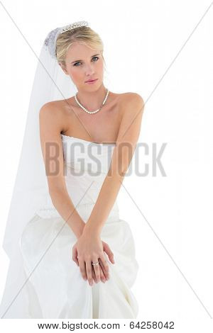 Portrait of beautiful sensuous bride in off shoulder dress sitting against white background