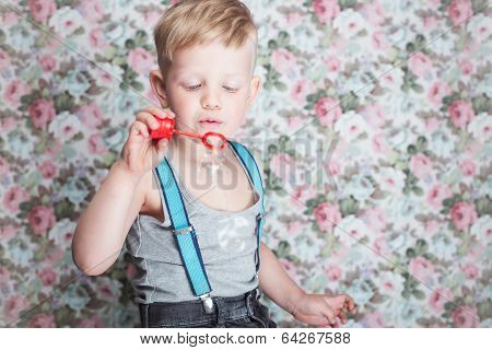 Portrait of funny little boy blowing soap bubbles