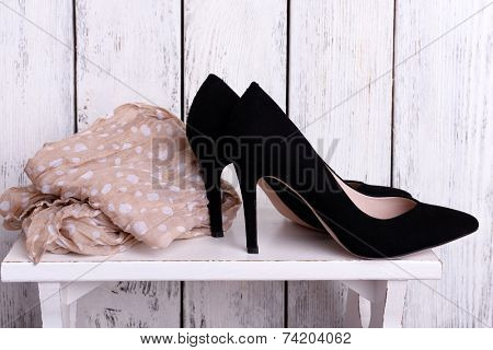 Black women shoes and scarf on bench on wooden background