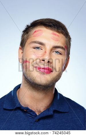 Portrait of young man with face full of lipstick marks of kisses