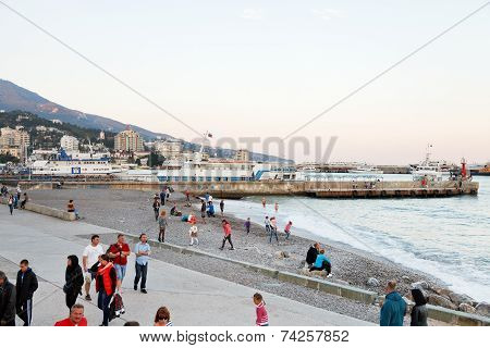 Tourists On Pebble Beach Of Yalta City In Evening