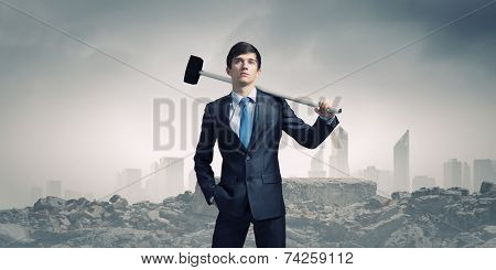 Young determined businessman with hammer in hands