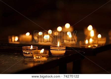 Rows of burning candles in a dim church
