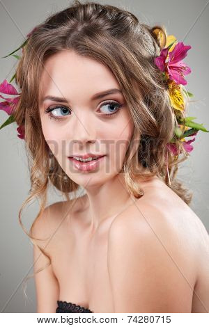 Beautiful girl, isolated on a light - grey background with varicoloured flowers in hairs, emotions, cosmetics