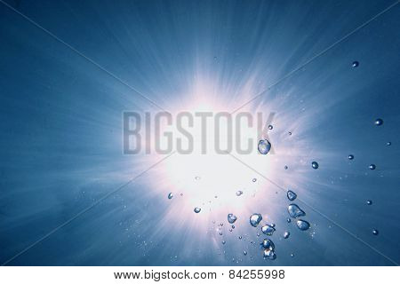 sun shines underwater with air bubbles in the sea