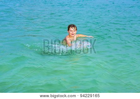 Handsome Boy Enjoys Sputtering With His Hand In The Tropical Ocean