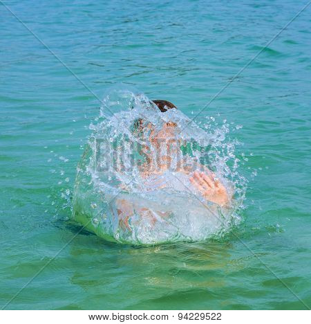 Handsome Boy Enjoys Sputtering With His Hand In The Tropical Ocean