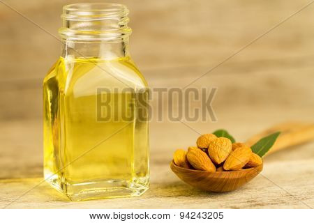 Peeled Almonds In A Spoon And Oil In A Jar On Wooden Background