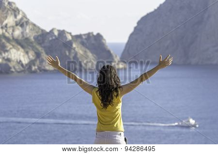 Young Happy Woman With Raised Hands And Looking The Sea.