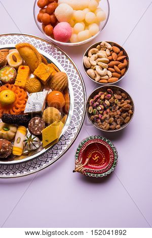 Mix Mithai and diya on diwali over colourful background
