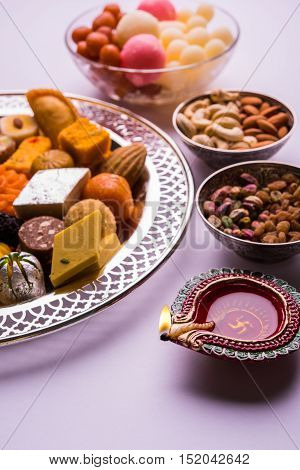 Mix Mithai and diya on diwali over colourful background