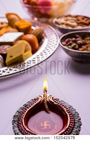 Mix Mithai and diya on diwali over colourful background