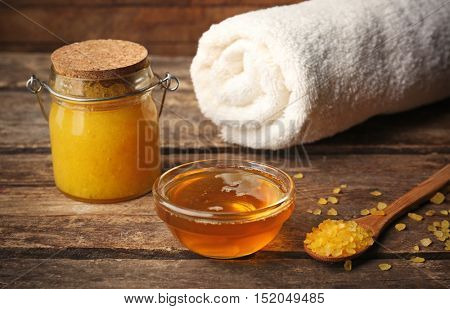 Body scrub and honey on wooden table