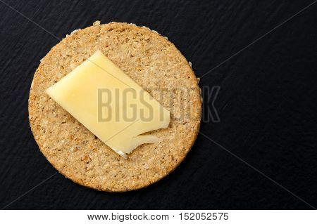 Single Scottish Oatcake With A Slice Of Yellow Cheese Isolated On Black From Above.