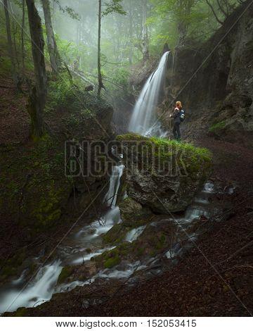 Hidden waterfalls in woods at fogy morning and solitude woman standing next to cascades on cliff. Popular travel destination Sopotnica Serbia.