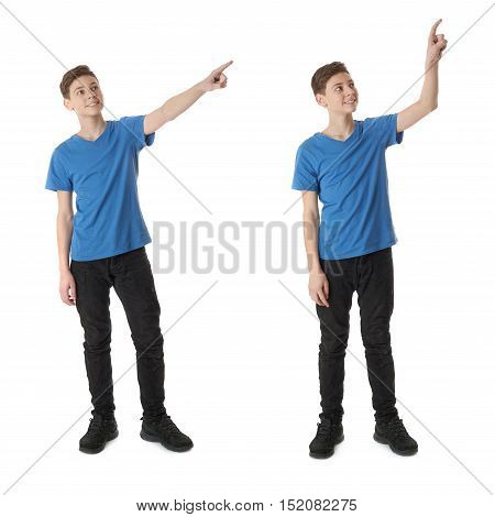 Cute teenager boy in blue T-shirt standing and poinitng up side over white isolated background full body