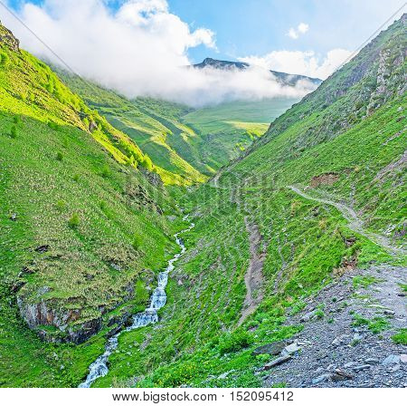 The tiny stream flows in gorge covered with clouds Stepantsminda Kazbegi Georgia.