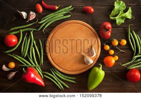 raw vegetables with cutting вoard on wooden background cooking