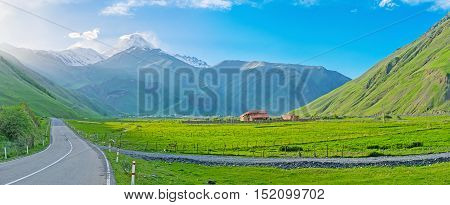 The green meadows of Sno valley with the sunset view on Kazbek Mount colored with the sun beams Kazbegi Georgia.