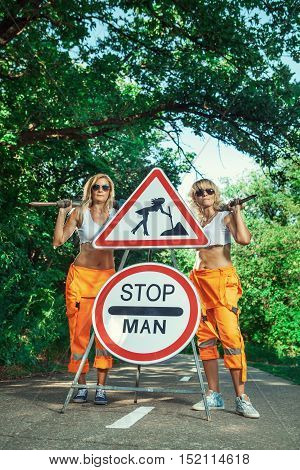 Two sexy women workers in overalls with the jackhammers.