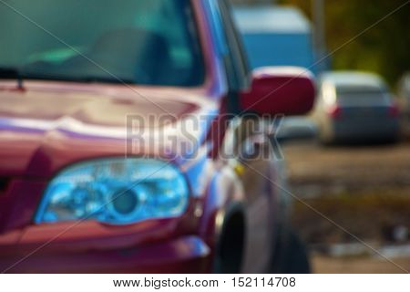 Red Car headlights and side blurred. The photo can be seen in the same side of the car