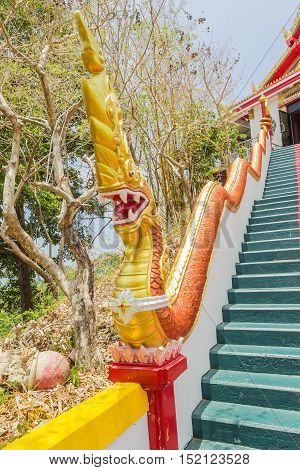 Phuket Thailand - April 25 2016 : Yellow Naka (giant snake) statue on top of main stair leading to the replica of Phra That In-Kwaen (Hanging Golden Rock) at Sirey temple Phuket Thailand.