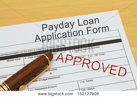 Applying for a Payday Loan Approved Payday loan application form with a pen on a desk with an approved stamp