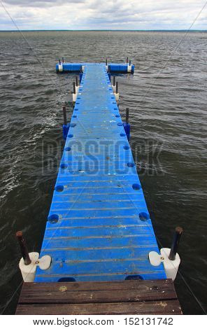 pontoon floating dock from blue plastic pontoons on a lake with waves