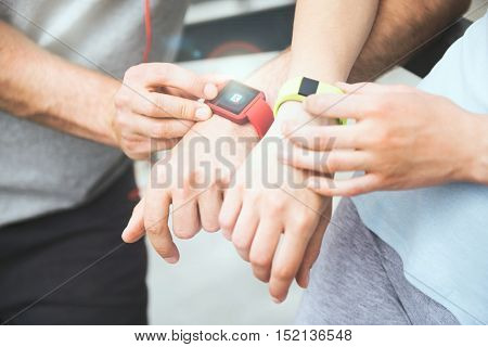 Sharing exercise performance. Active and sporty couple looking at their smartwatches and sharing data after working out outdoors