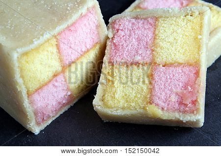 Freshly Cut Battenberg Cake On Dark Slate Board. Pink And Yellow Sponge Covered In Marzipan