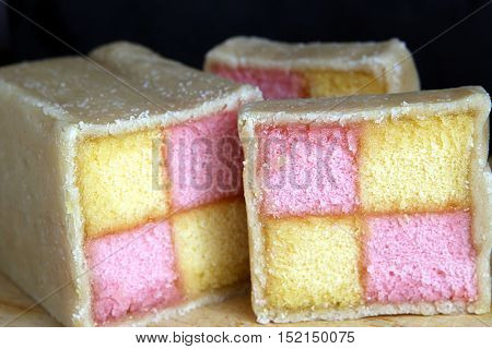 Freshly Cut Battenberg Cake Slices On Wooden Board With Dark Background. Pink And Yellow Sponge Cove