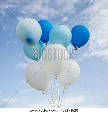 Colorful party balloon floating in mid air against blue sky.