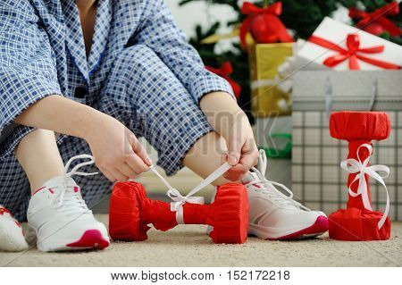 Woman In Pajamas And Athletic Shoes Unties The Bow On The Dumbbells.