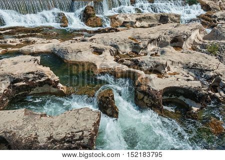At the foot of the hill on which La Roque sur Cèze in France lies swirl spectacular waterfalls and rapids of the Cascades du Sautadet.