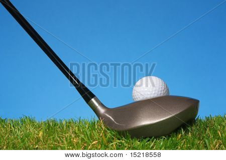 Klaar om te rijden een golfbal uit een tee met gras en een blauwe achtergrond.