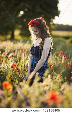 Beautiful young woman on the poppy field in sunlight