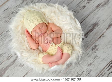 sweet newborn baby in hat and panties sleeping on round bed, top view