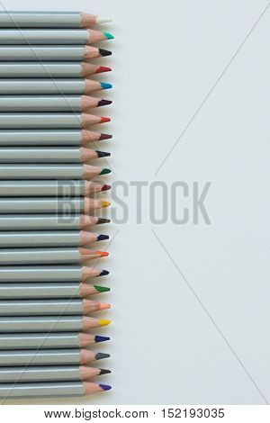 Palisade of colored pencils on the white piece of paper. Background