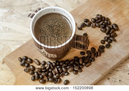 freshly ground coffee brewed in a cup on a wooden board