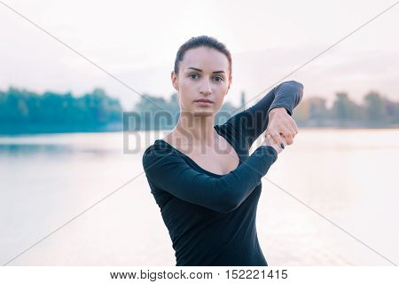 Young Fitness Woman Stretches On Pier During Workout At Dawn