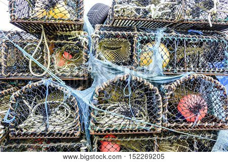 Textures and colors of stack of lobster pot creels on the Isle of Skye Scotland with tangled ropes and blue netting and colorful buoys