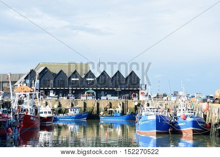 Whitstable United Kingdom -October 1 2016: Fishing Boats in Whitstable Harbour with row of warehouses in background