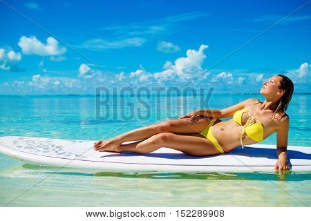 Woman in bikini sunbathing on the paddle board in Exuma, Bahamas