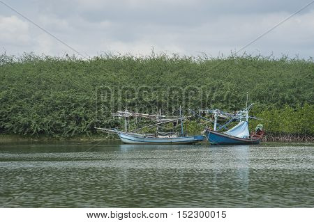 traditional fishing boat on the sea with mangrove forest in background.cloudy sky.fitered image.selective focus
