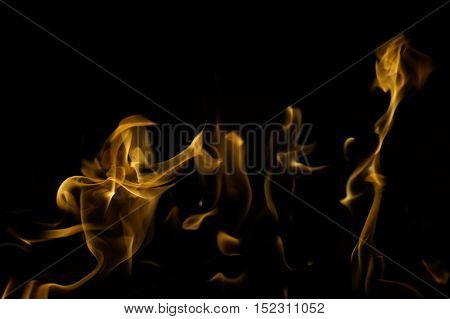 Snapshot of yellow, flickering tongues of fire dancing and twisting on black background