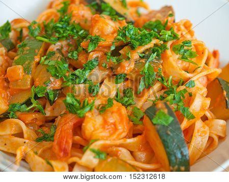 Tagliatelle with zucchini and shrimps on a white plate